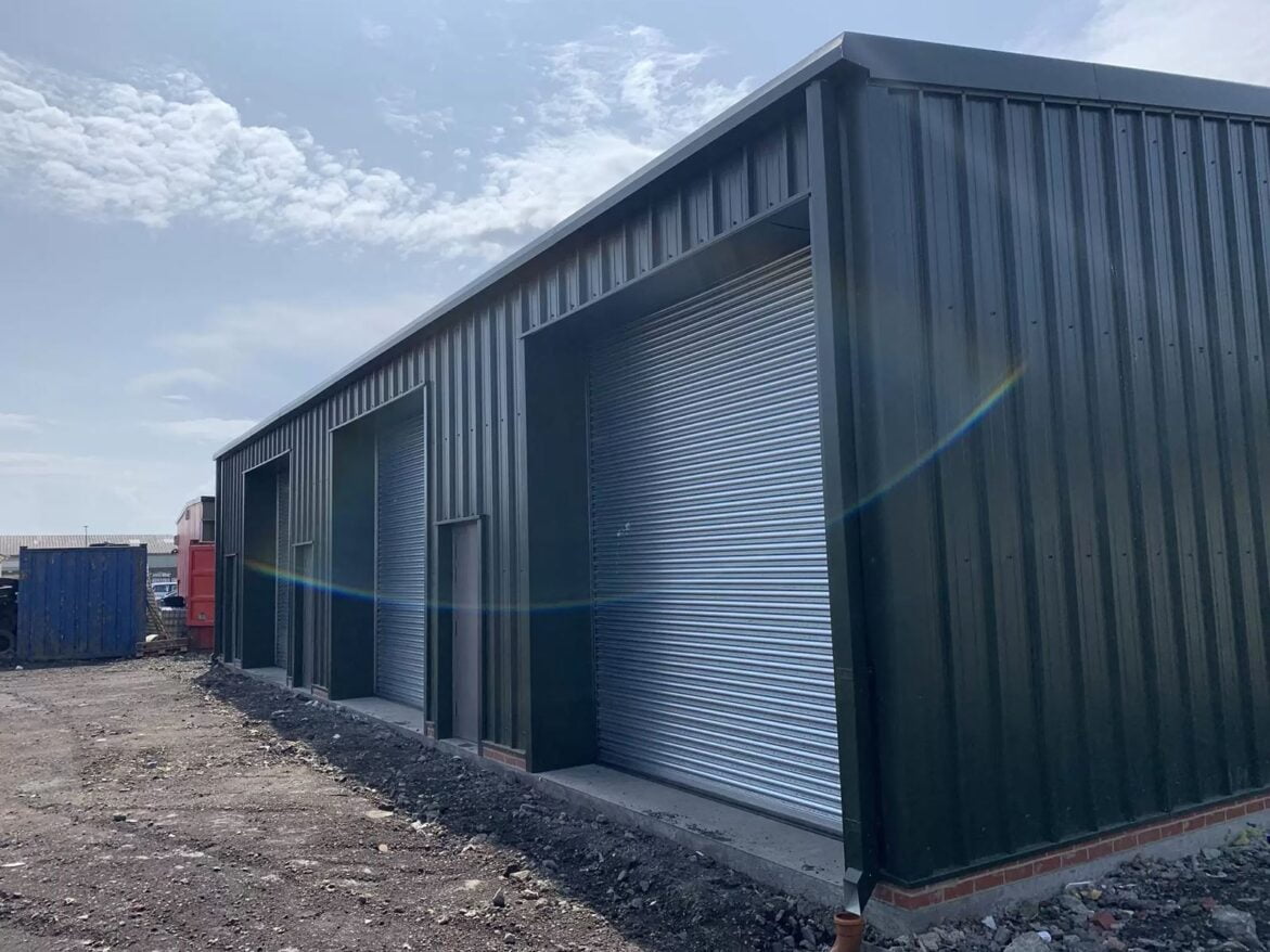 A close up view of a steel building with numerous industrial roller shutter doors.
