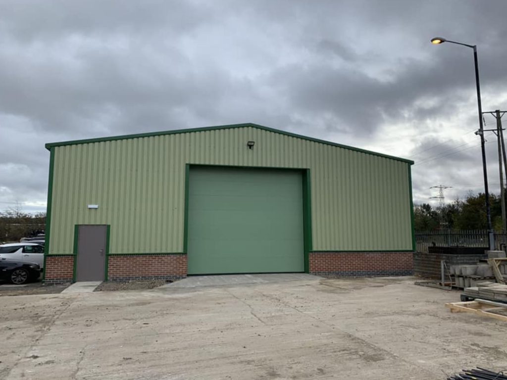 Completed green-clad steel commercial building with roller shutter door, built by Hamilton Steel