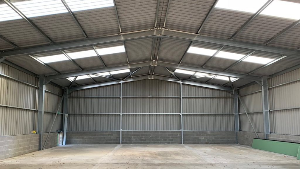 A well-lit empty steel building with skylights.
