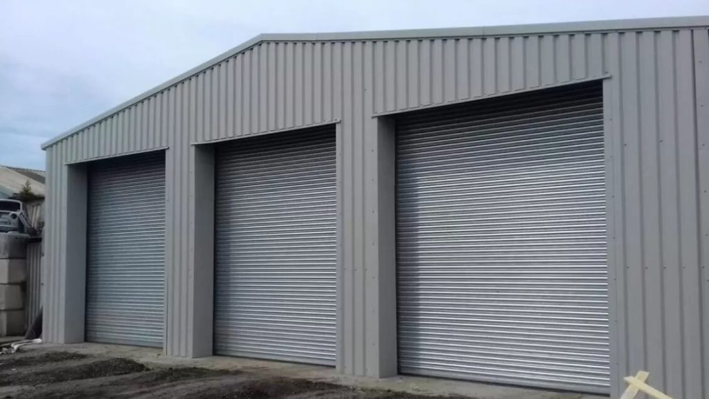 A grey steel storage building with three roller shutter doors that has been designed and installed by Hamilton Steel.