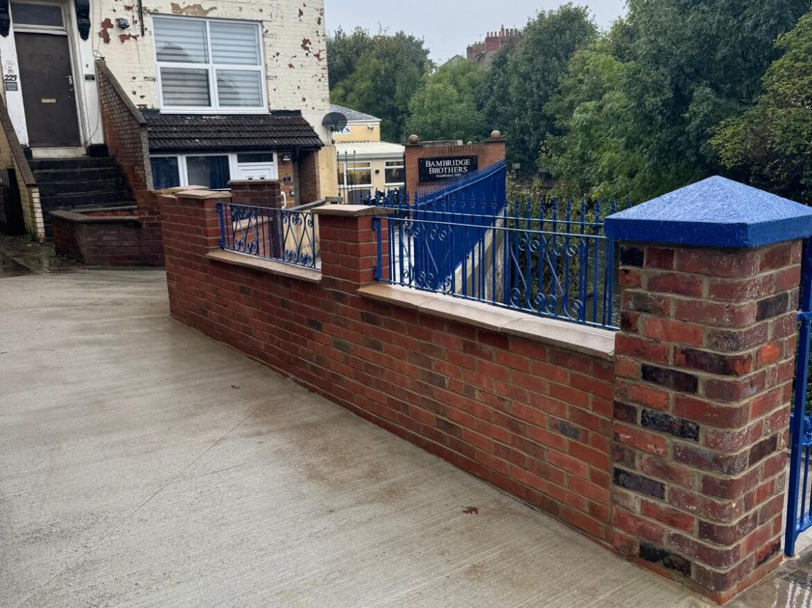 Completed concrete walk way with new brick wall and railings