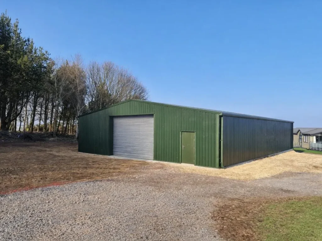 Green steel building with roller shutter for Haystax Holiday Park