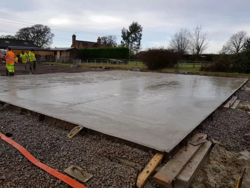 Freshly poured concrete slab for the new farm building with the farmhouse behind at Lewhurst Farm
