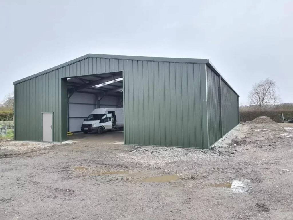 Green clad agricultural steel building at Lewhurst Farm with a van parked inside the open bay
