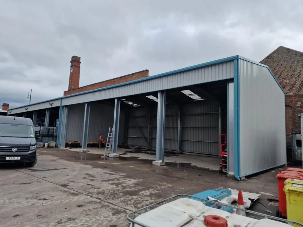Bespoke steel extension with blue trim and open bays built onto the existing brick building at Oil Salvage Ltd