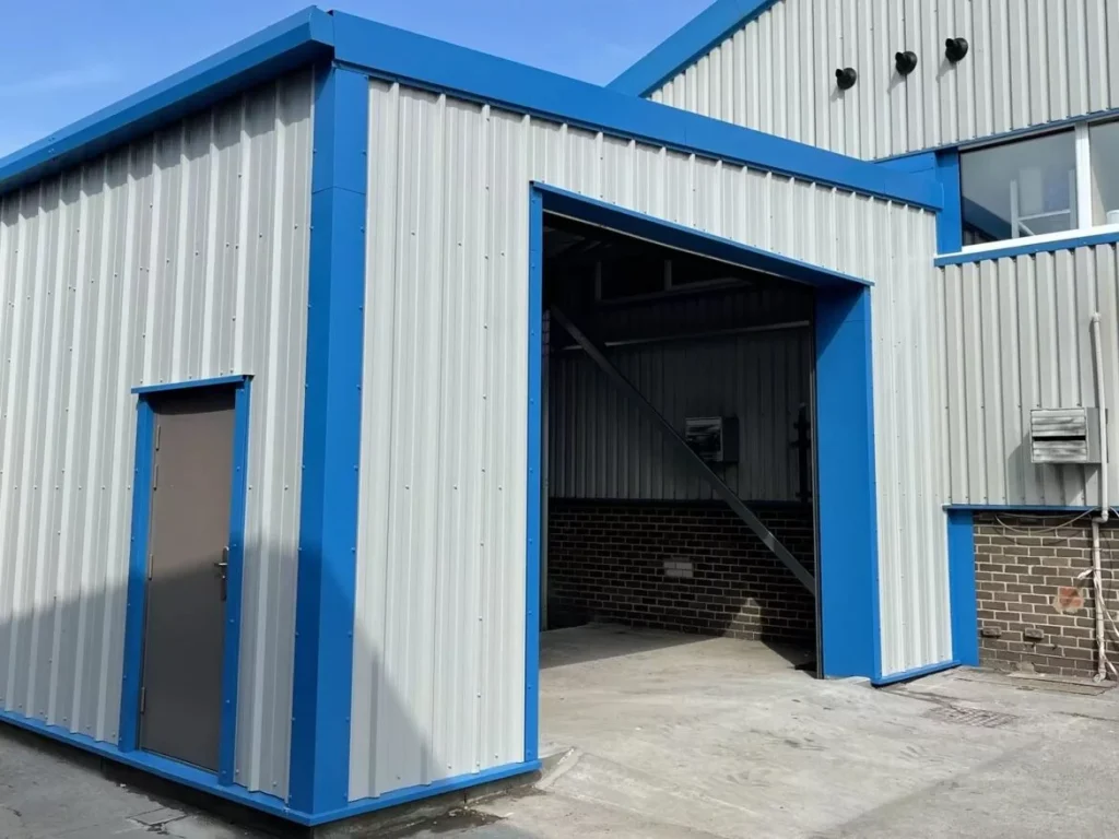 Steel building extension with open bay and personnel door in blue and grey cladding at Simply Food Solutions