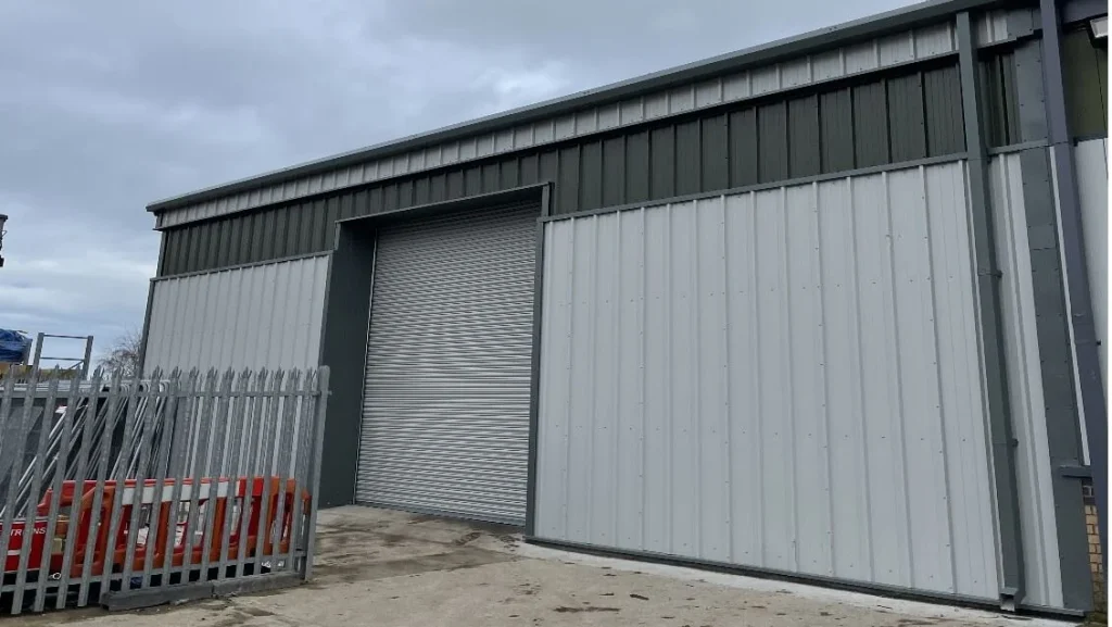 St Astier Ltd steel building with grey and green cladding and a new roller shutter door