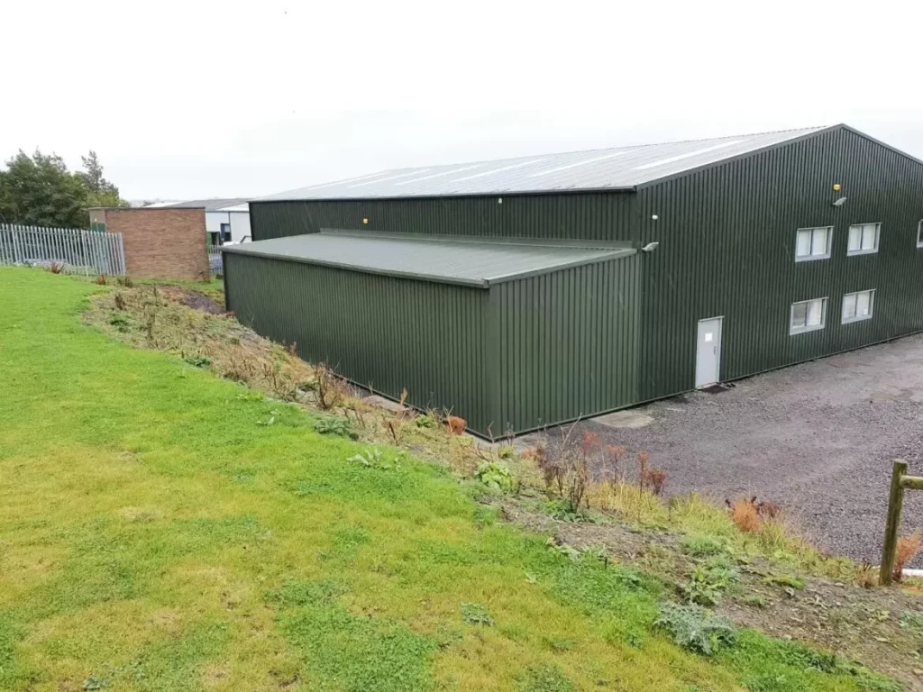 Green clad steel building with attached office block and lean-to extension for Sustain Landscapes Ltd