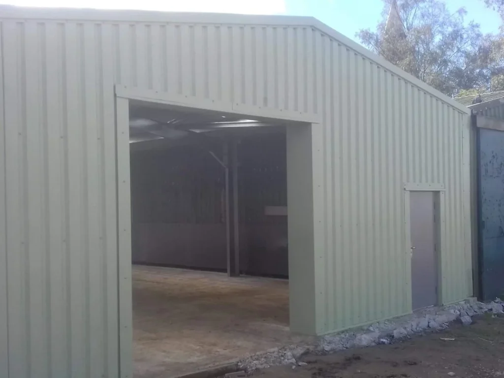 Sage green clad steel building with a tall open bay for S W Yorke and Sons Ltd