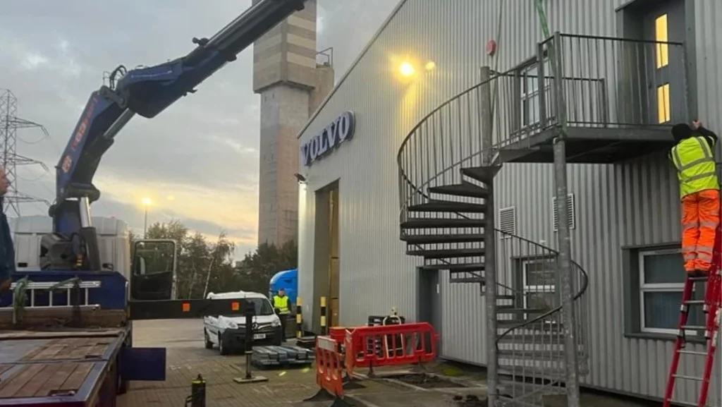 Crane lifting materials during external works at the Volvo Truck and Bus Centre, with a new spiral staircase in place