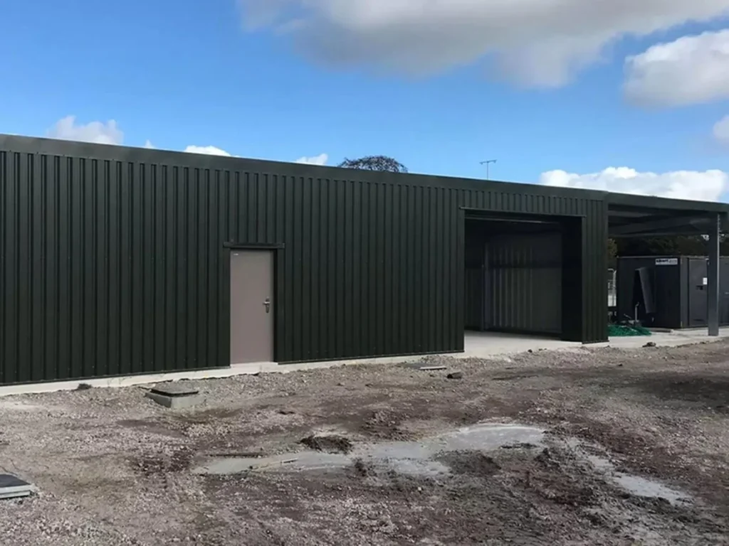 Completed dark green clad steel building with personnel door and roller shutter opening for the Welsh Football Association
