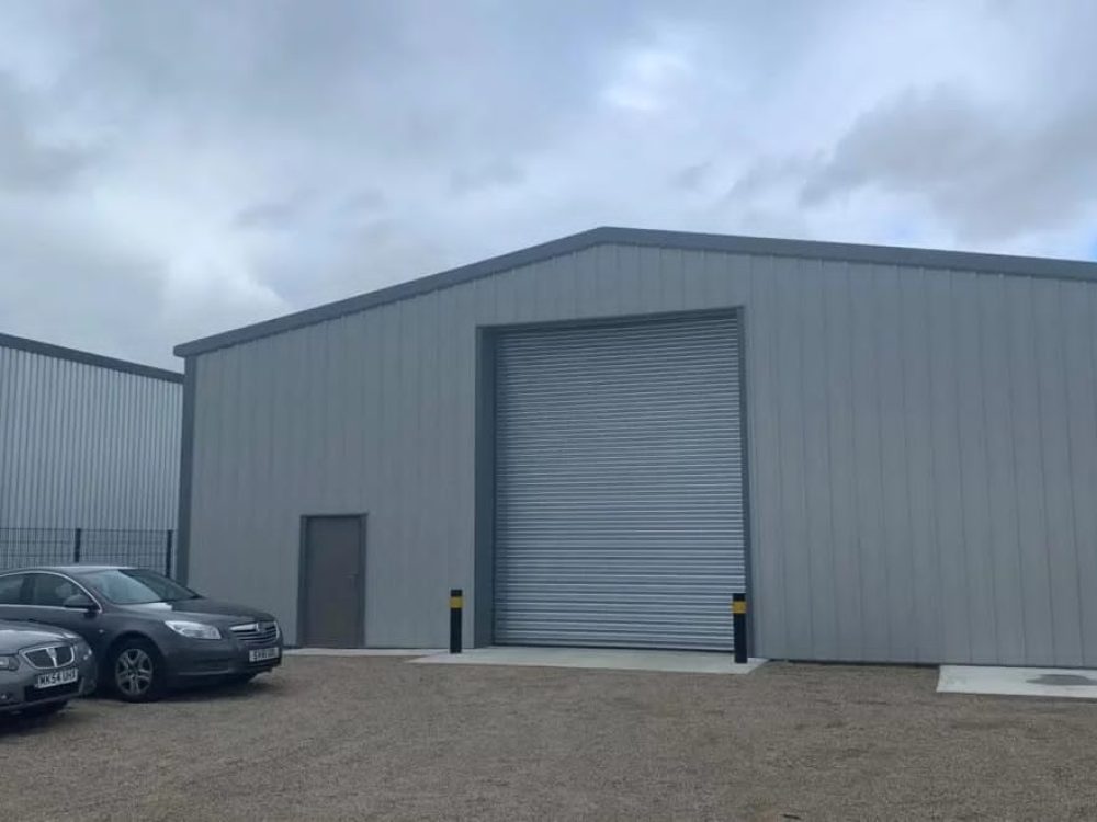 A wide exterior view of a successfully completed and handed over industrial steel building project, featuring modern metal cladding and clean landscaping.