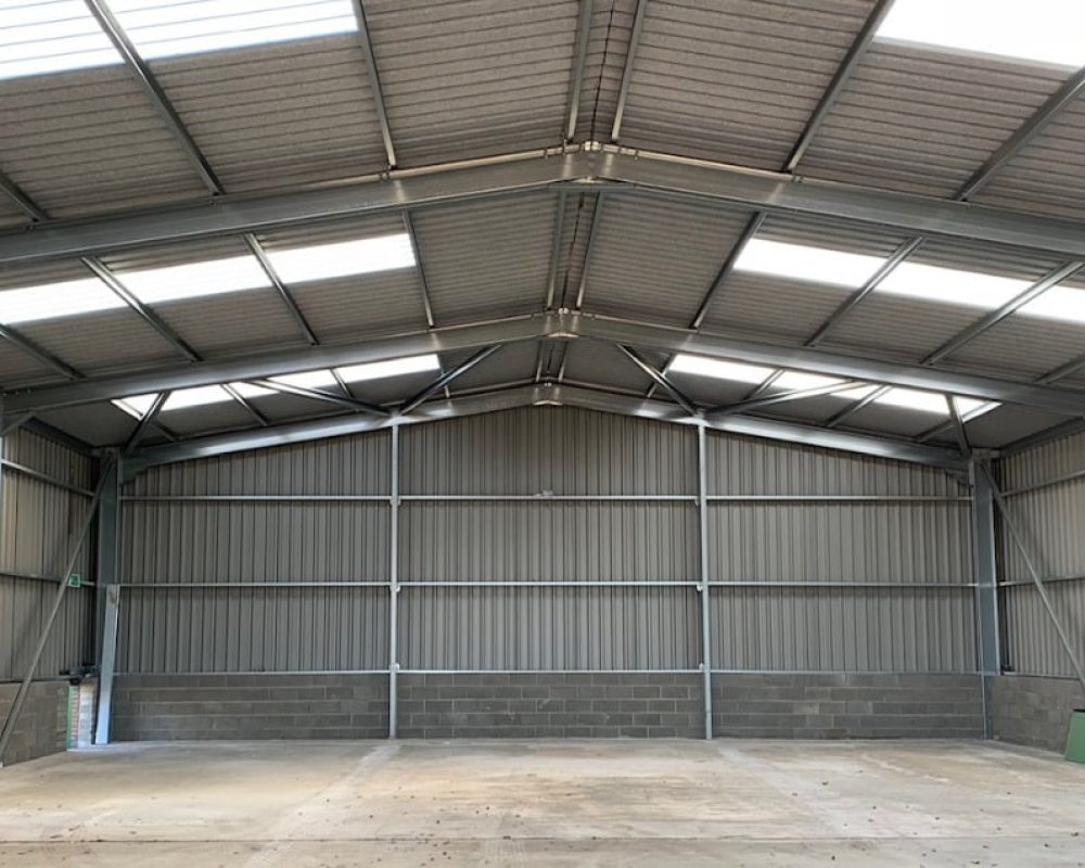 A well-lit empty steel building with skylights.