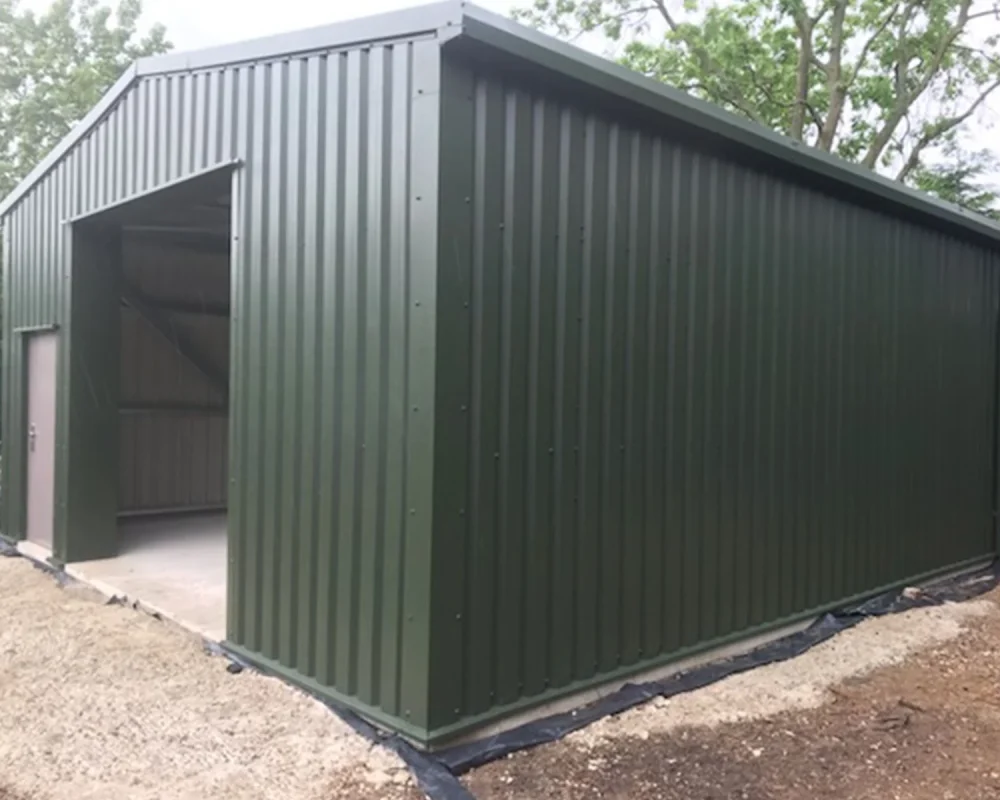Green steel building with open bay for AL Fencing