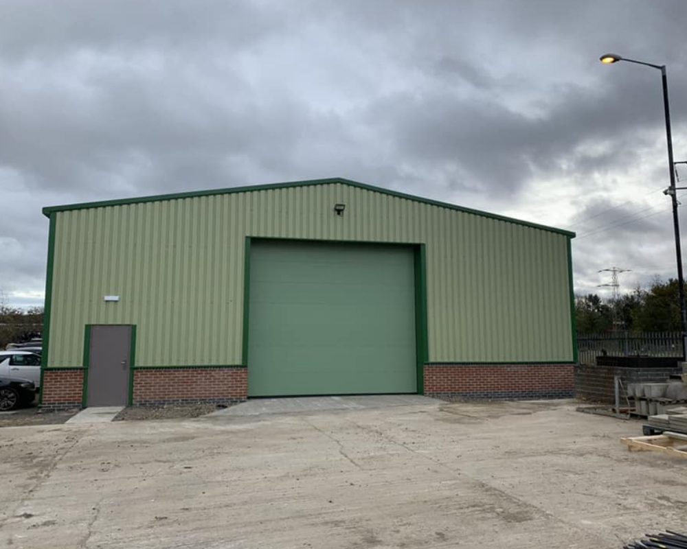 Completed green-clad steel commercial building with roller shutter door, built by Hamilton Steel