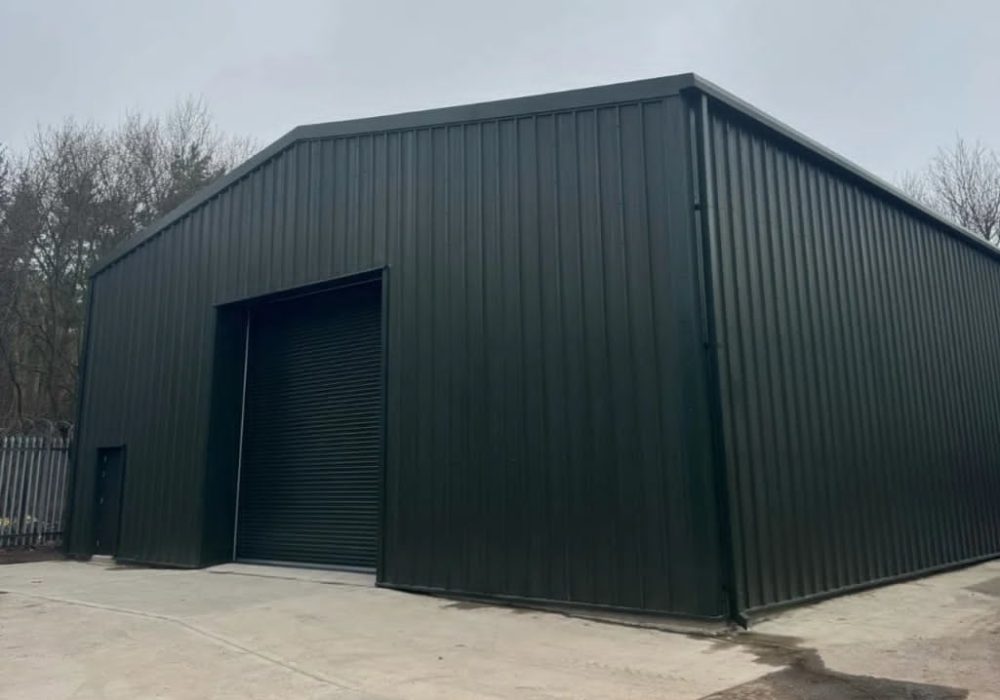 Dark green steel building with roller shutter and personnel door