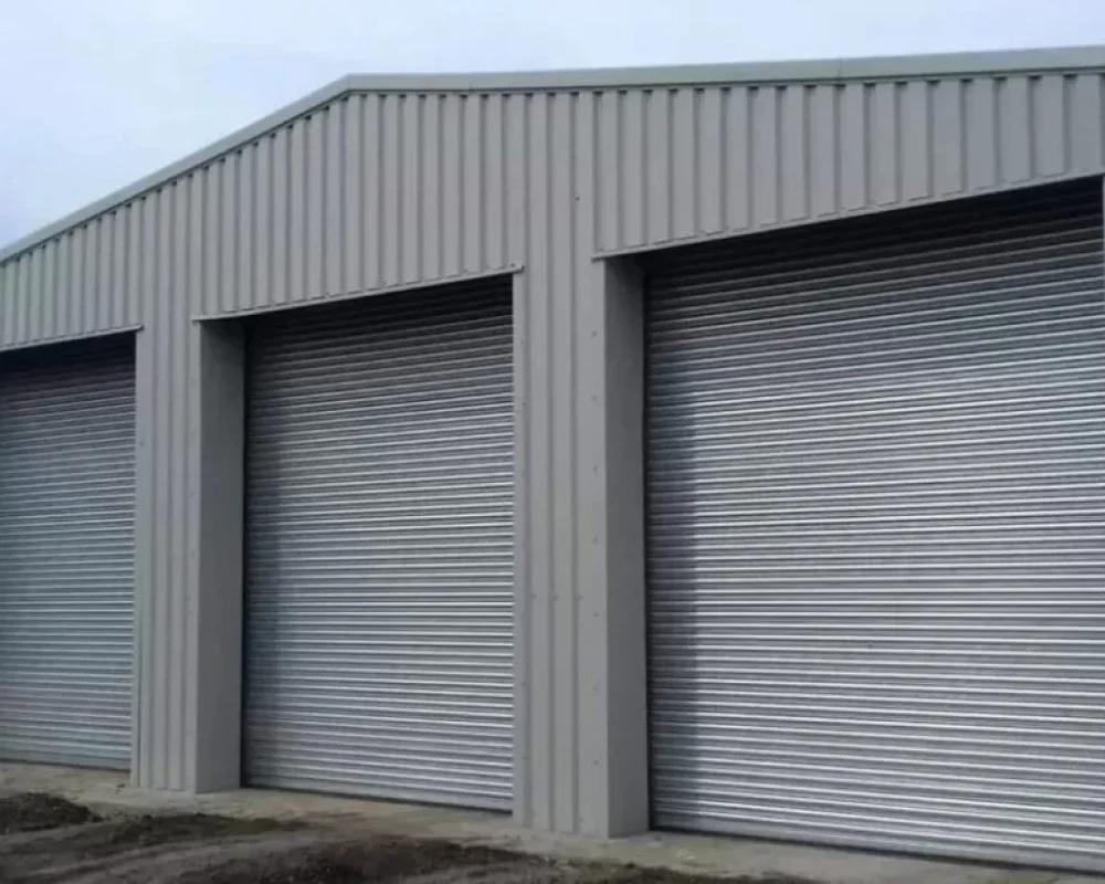 Grey steel storage building with three roller shutter doors