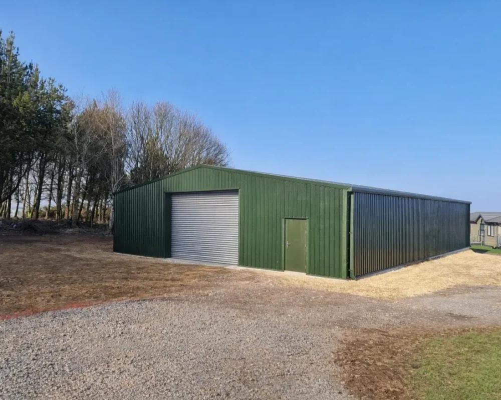Green steel building with roller shutter for Haystax Holiday Park