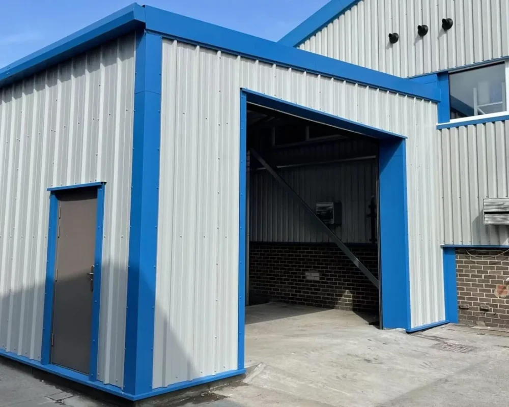 Steel building extension with open bay and personnel door in blue and grey cladding at Simply Food Solutions