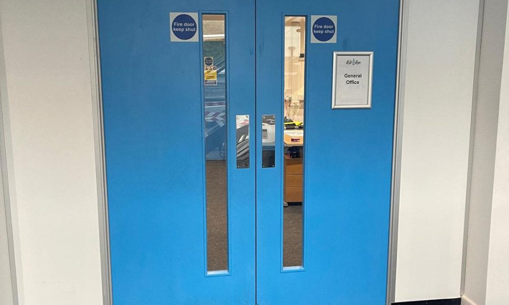 Blue fire doors marked 'keep shut' fitted inside a steel building office area