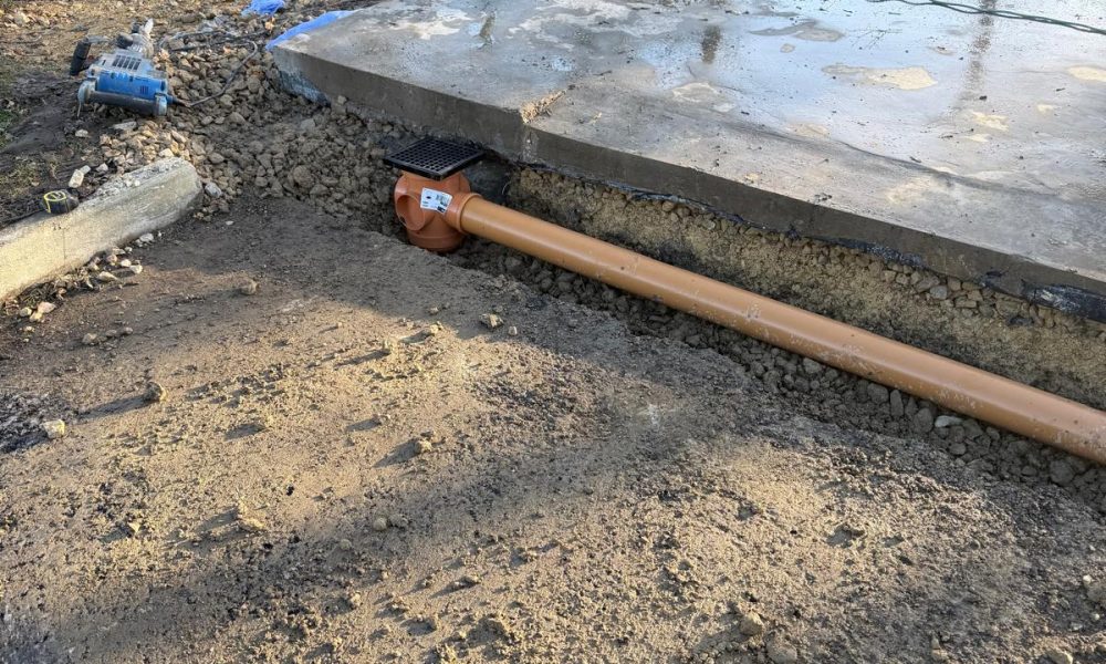 Underground rainwater drainage pipe and gully installed beneath a new concrete steel building base