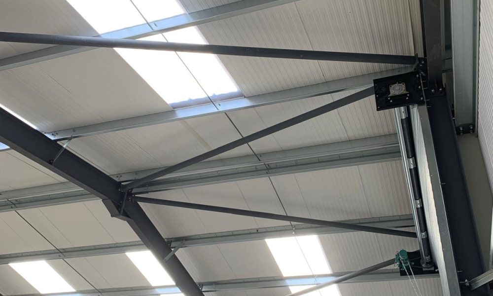 Interior view of steel roof trusses with translucent rooflight panels letting in natural light