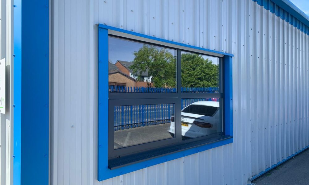 Aluminium-framed window fitted into a steel building's blue and white cladding