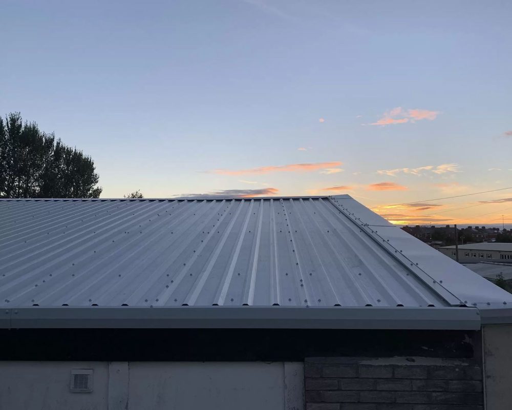 Close-up of a green corrugated steel roof on a Hamilton Steel garage building at sunset