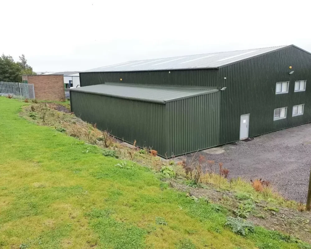Green clad steel building with attached office block and lean-to extension for Sustain Landscapes Ltd