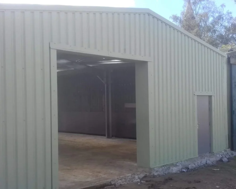 Sage green clad steel building with a tall open bay for S W Yorke and Sons Ltd