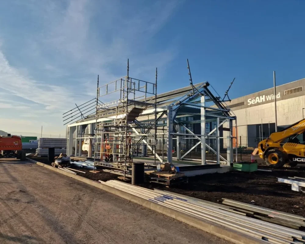 Teesworks HV building steel frame with scaffold edge protection in front of the SeAH Wind facility